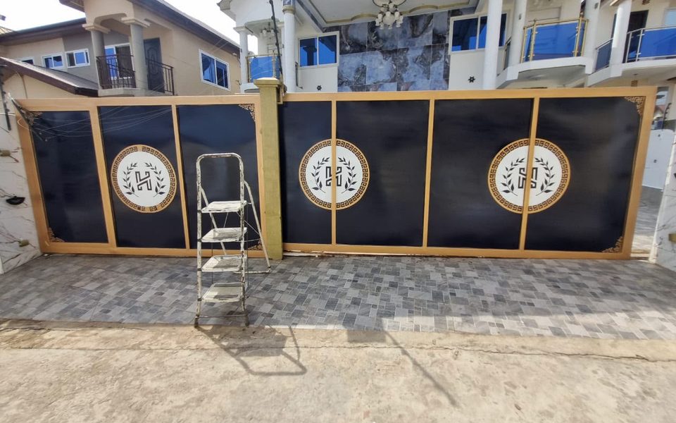 Black and gold sliding gate with monogram emblems