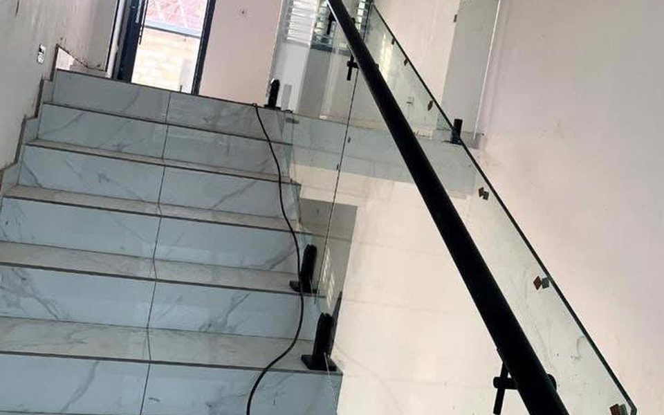 Frameless glass staircase balustrade with black handrail