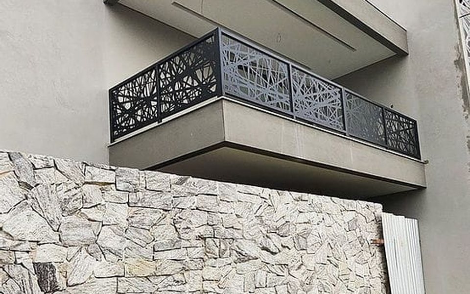 Laser-cut steel balcony railing above a stone wall
