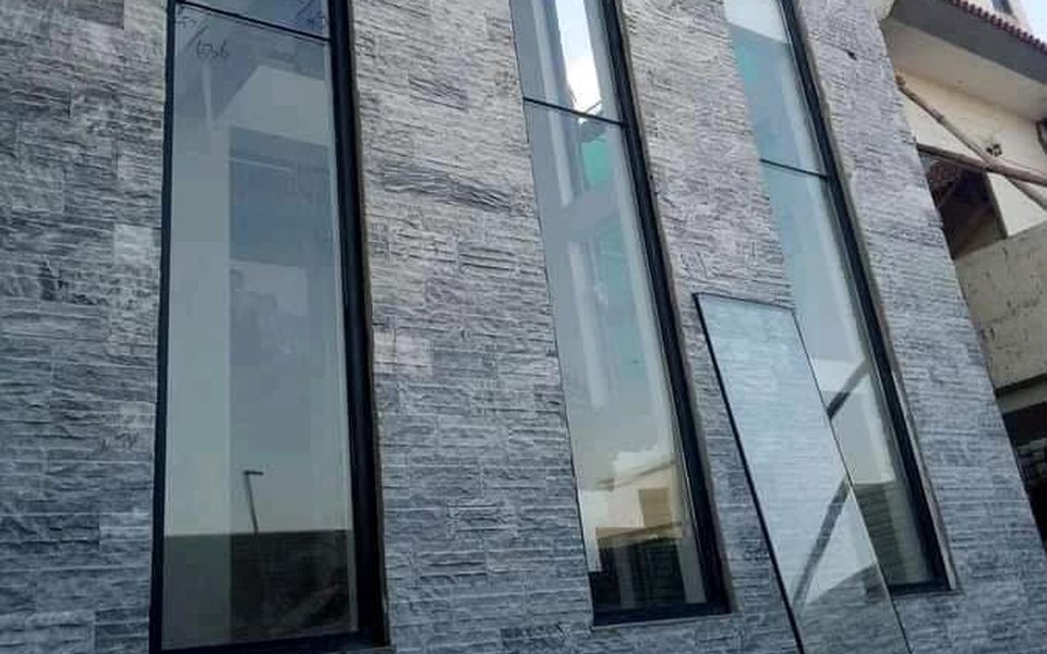 Tall glazed window panels set in a stone-clad facade