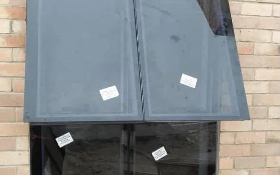 Tinted glass canopy over a glazed window on a brick wall