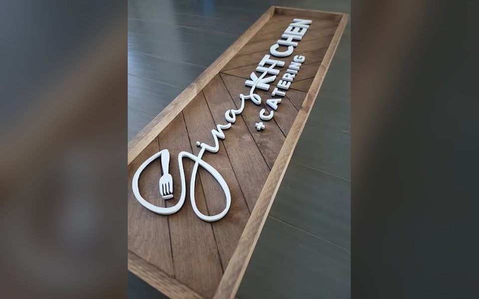 White 3D lettering and logo mounted on a herringbone wooden panel
